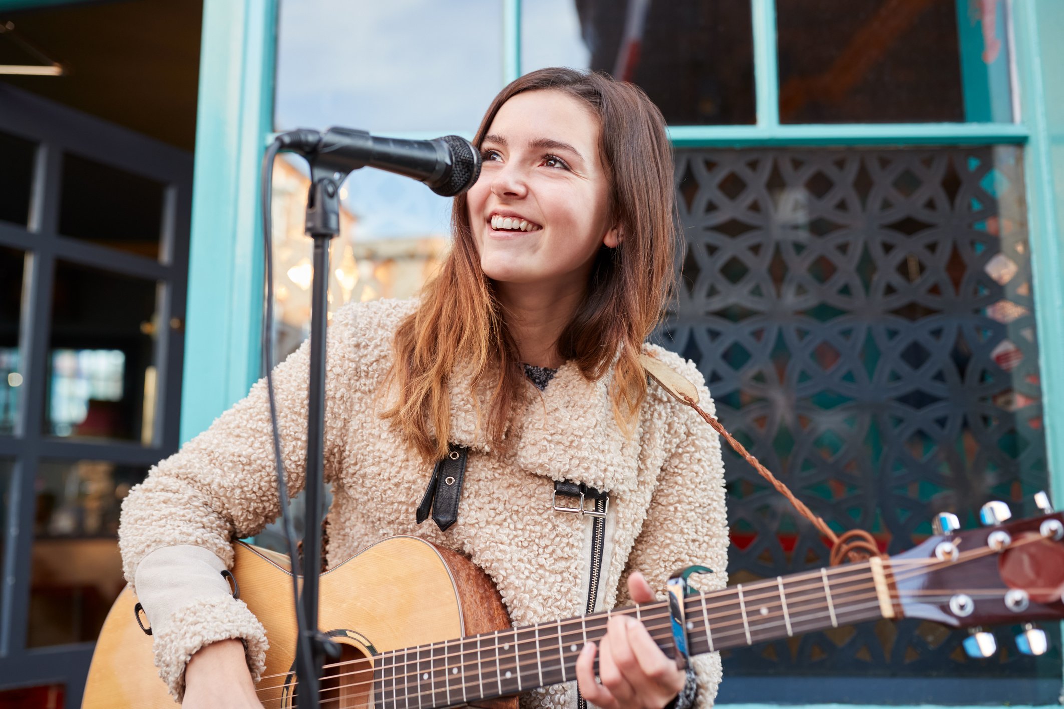 Female Musician Busking Playing Acoustic Guitar and Singing Outd
